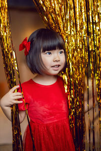 Portrait of a beautiful korean baby girl in a red dress at christmas with a gold decoration