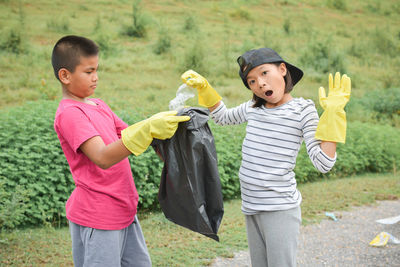 Children collecting garbage on grassy field