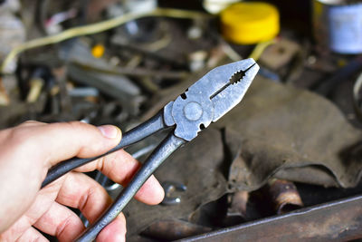 Black iron pliers in hand in the garage