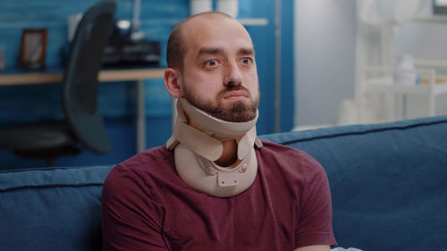 Man with neck brace sitting at home