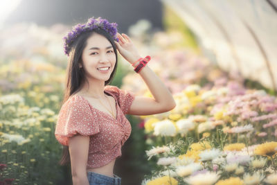 Beautiful young woman standing by flowering plants