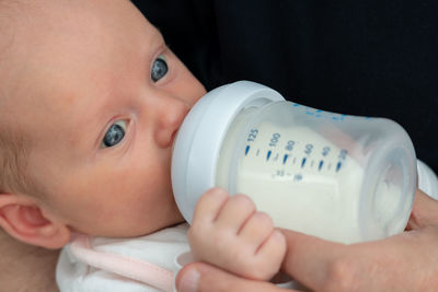 Close-up of cute baby boy holding bottle