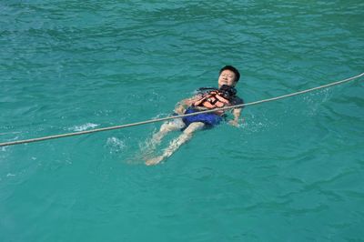 High angle view of man swimming in sea by rope