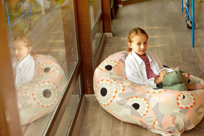 Cute girl sitting in bean bag near window