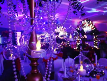 Close-up of illuminated lights hanging on glass