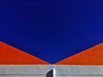 Low angle view of multi colored wall against clear blue sky