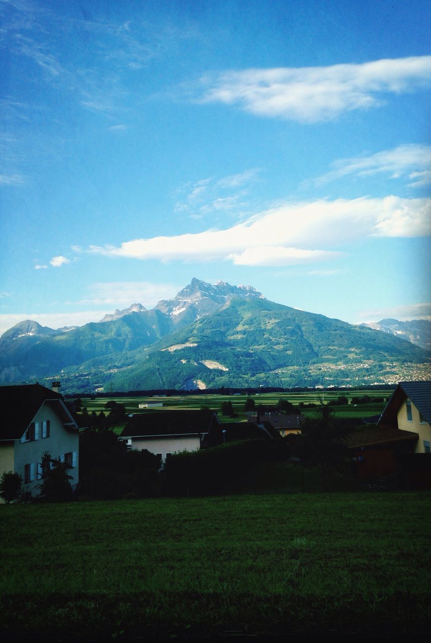 mountain, architecture, built structure, building exterior, sky, mountain range, landscape, house, grass, cloud - sky, field, cloud, nature, beauty in nature, scenics, tranquil scene, tranquility, blue, day, residential structure