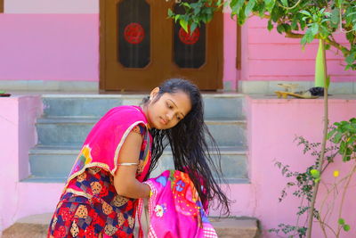 Happy girl standing against pink wall