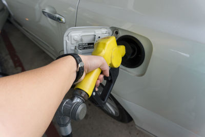 Cropped hand of person fueling car at gas station