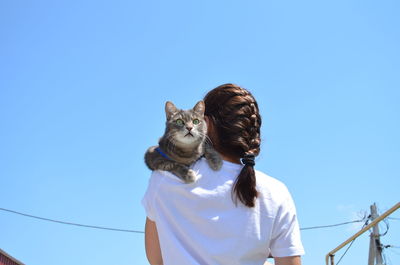 Woman with umbrella against clear blue sky