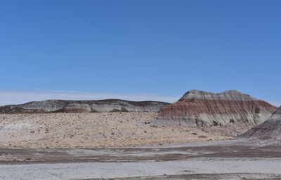 Scenic painted desert with colorful layers of rock sediment in a valley.