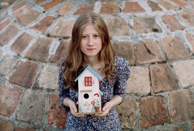 Portrait of girl standing against brick wall