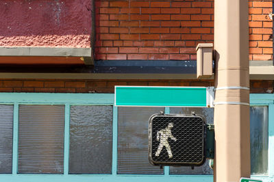 Walk signal on metallic pole against building in city