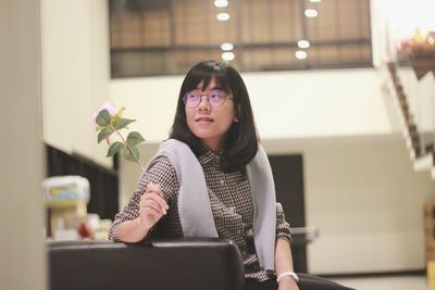 Portrait of smiling young woman standing against wall