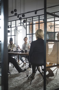 Female entrepreneur discussing with colleagues seen through doorway of startup company