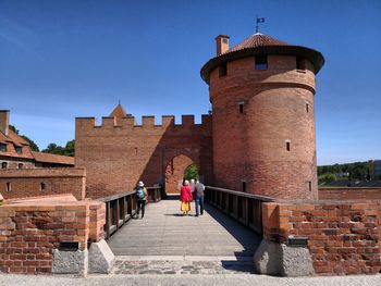 Rear view of women walking on the passage against building