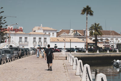 Rear view of people walking on street amidst buildings in city