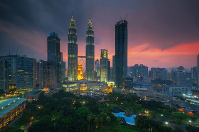 Illuminated buildings in city against sky during sunset