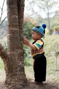 Side view of boy standing on tree trunk
