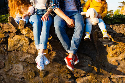 Low section of people sitting on rock