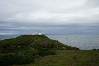 Lighthouse amidst sea and buildings against sky