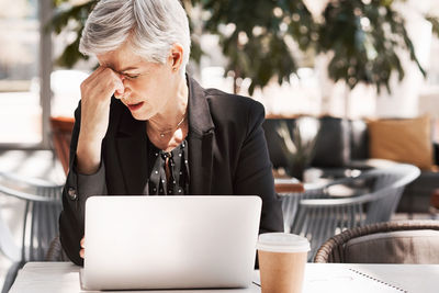 Midsection of woman using mobile phone while sitting on table