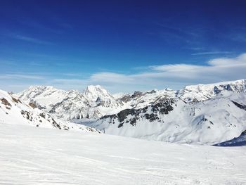 Scenic view of snowcapped mountains against blue sky