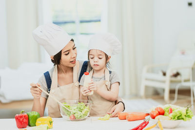 Full length of mother and daughter in kitchen