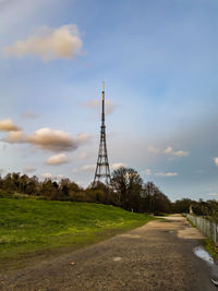 Windmill on road amidst field against sky