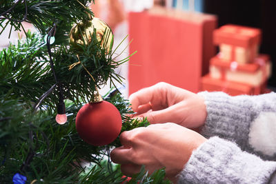 Cropped hand of woman hanging decoration on christmas tree