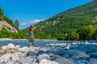 Rear view of woman standing on rock against sky