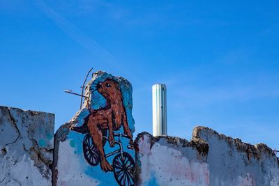 Low angle view of graffiti against blue sky