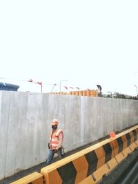 Worker working on construction site against clear sky