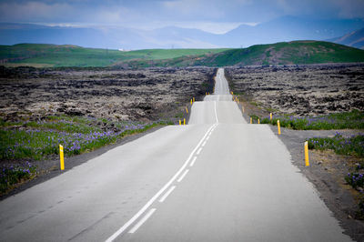 Road leading towards mountain against sky