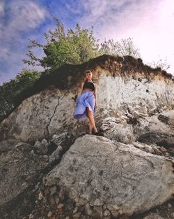 Full length of girl standing on rock against sky