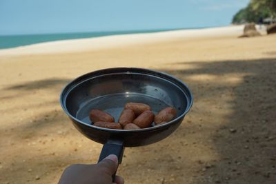 Midsection of person holding ice cream on beach