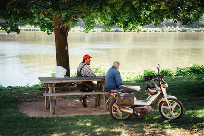 Friends sitting on bench at lakeshore