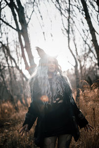 Young woman standing against tree during autumn