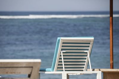 Chair on beach against sky