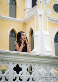 Portrait of young woman standing against building