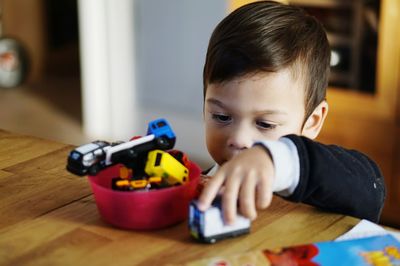 Close-up of boy playing with toy car at home