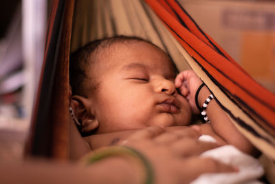 Cropped hands of woman touching cute baby boy sleeping on hammock