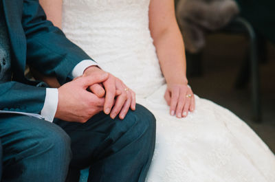 Midsection of newlywed couple holding hands in wedding ceremony