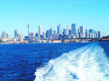 Sea and buildings against clear blue sky