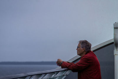 Side view of man looking at sea against sky
