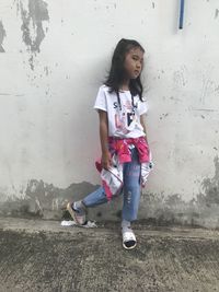 Portrait of girl standing against wall