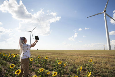 Blogger girl with bright braids shoots story about green energy, wind energy and wind turbines