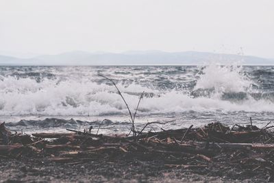Scenic view of waves splashing on shore against sky