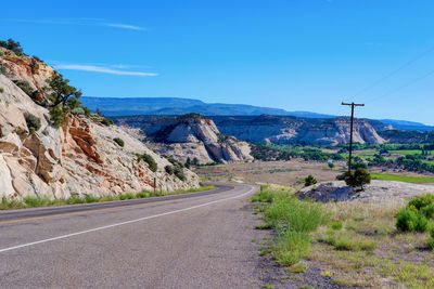 Road leading towards mountains against blue sky