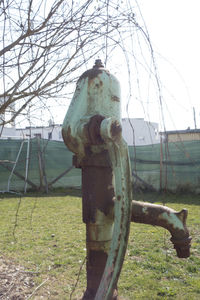 Close-up of rusty metal fence on field against sky